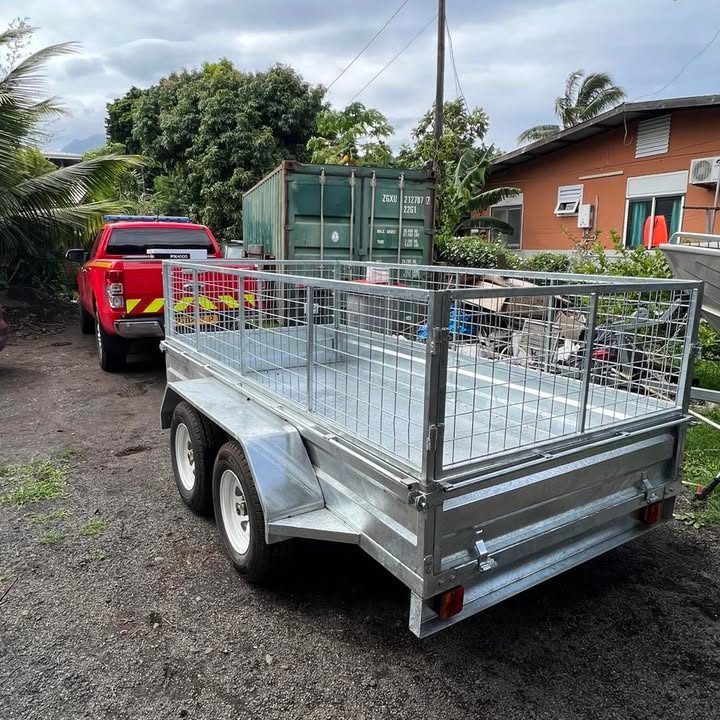 Remorque benne grillagée double essieu attelée à un pick-up rouge